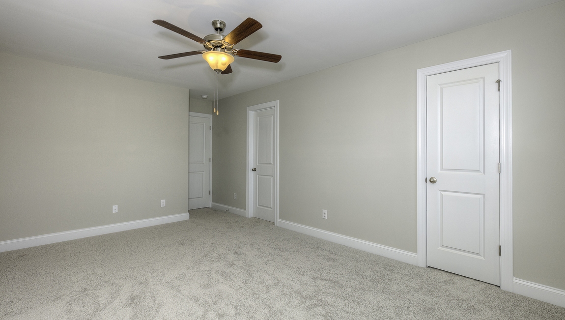 Carpeted bedroom with ceiling fan and small window