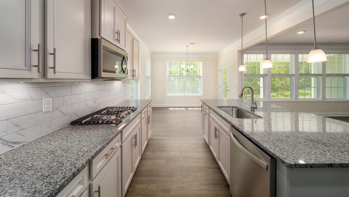 Kitchen and island with white cabinets, granite countertops, and stainless steel appliances