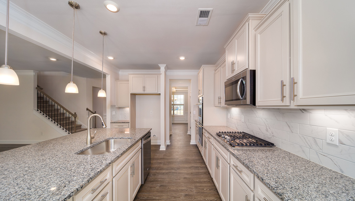 Kitchen and island with white cabinets, granite countertops, and stainless steel appliances