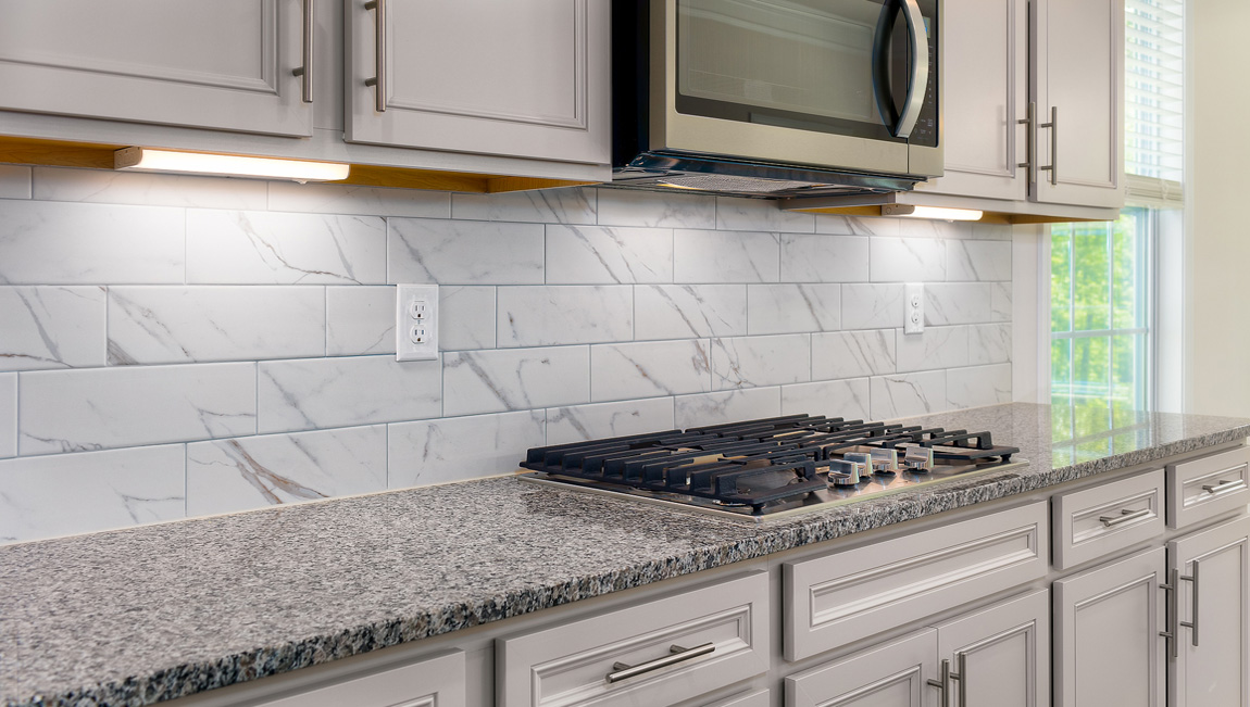 Kitchen and island with white cabinets, granite countertops, and stainless steel appliances