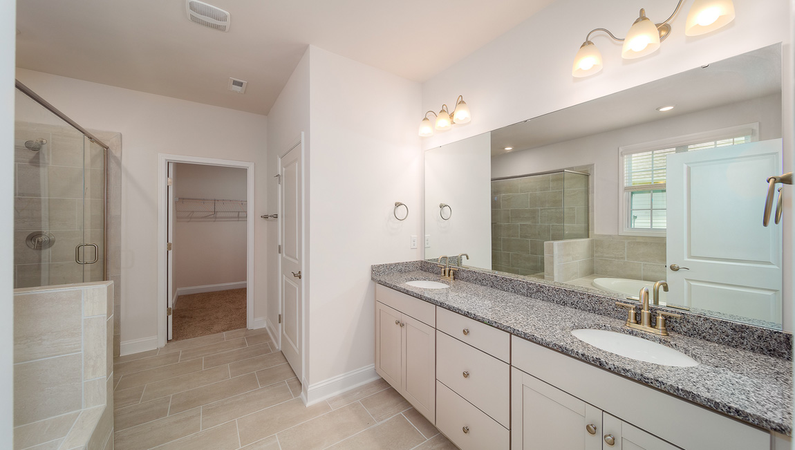 Primary bathroom with double sink vanity, large bathtub and standing glass door shower