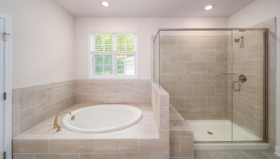 Primary bathroom with double sink vanity, large bathtub and standing glass door shower