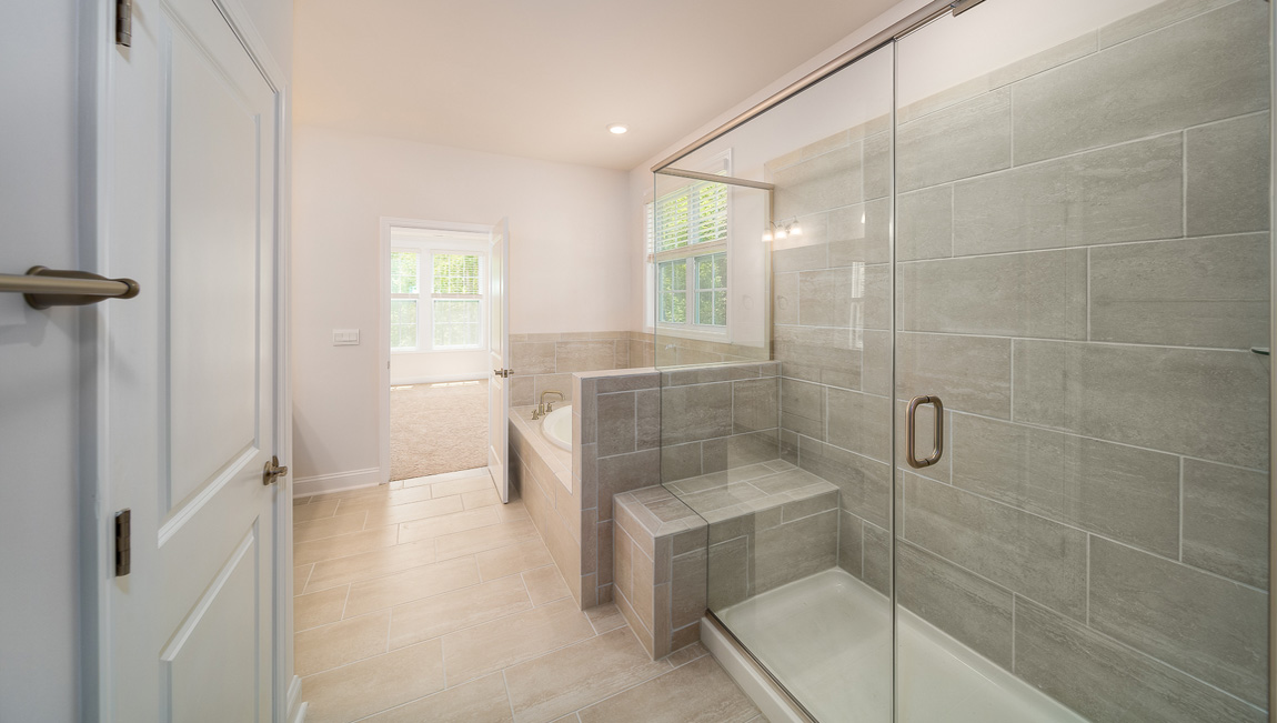 Primary bathroom with double sink vanity, large bathtub and standing glass door shower