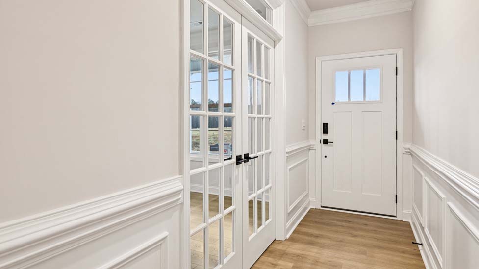 Welcoming foyer with wood floors, view of front door, and edge of dining room