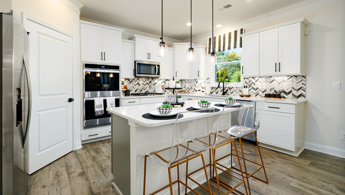 Kitchen and island with wood floors, white cabinets, quartz counters, and stainless steel appliances