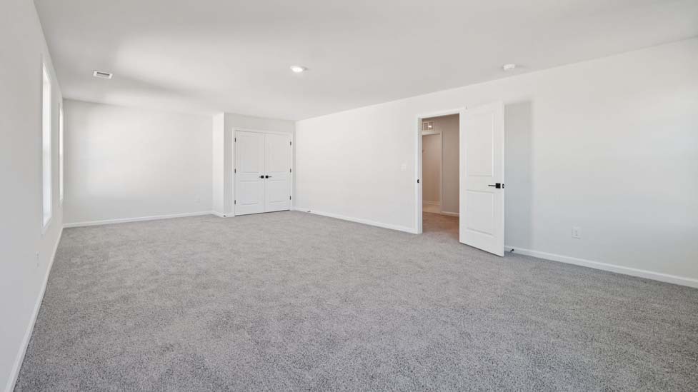 Primary carpeted bedroom with large windows