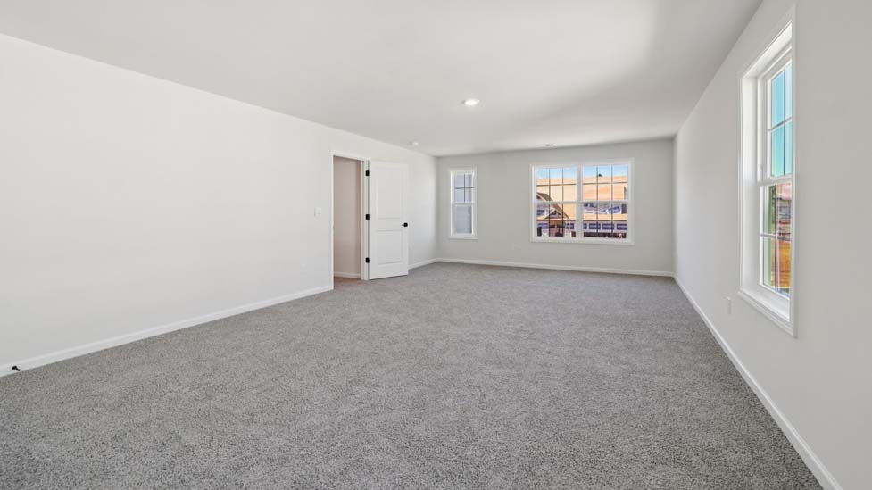 Primary carpeted bedroom with large windows
