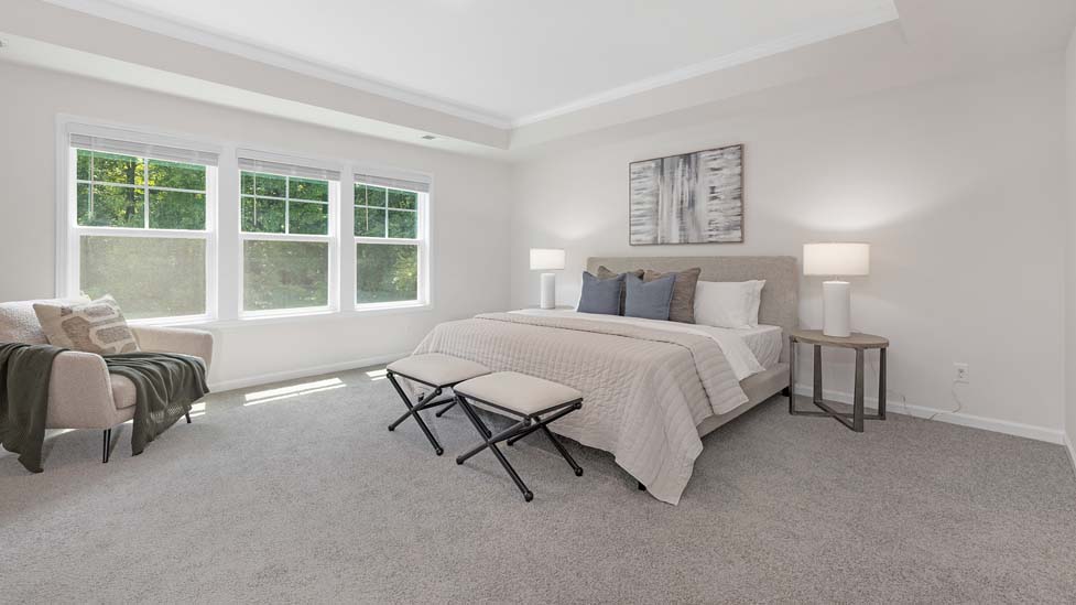 Primary bedroom with carpet, large windows, and seating area