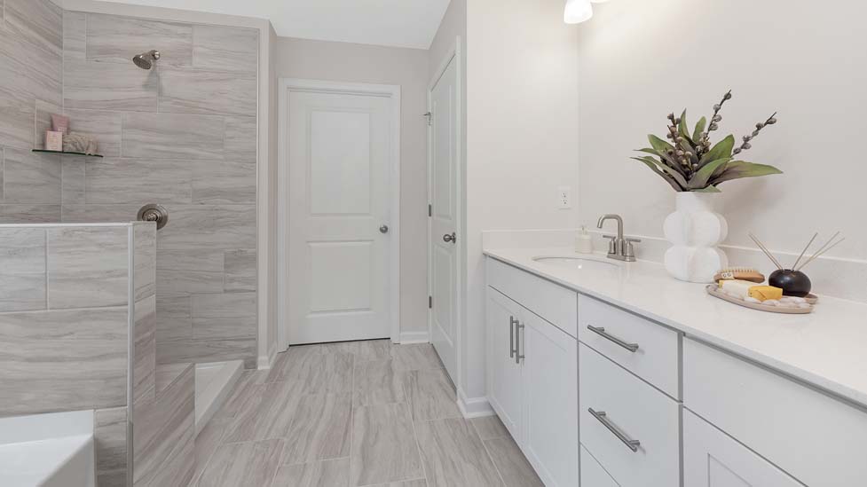 Primary bathroom with white cabinets, large bathtub ad shower