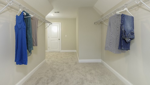 Primary carpeted walk in closet with window