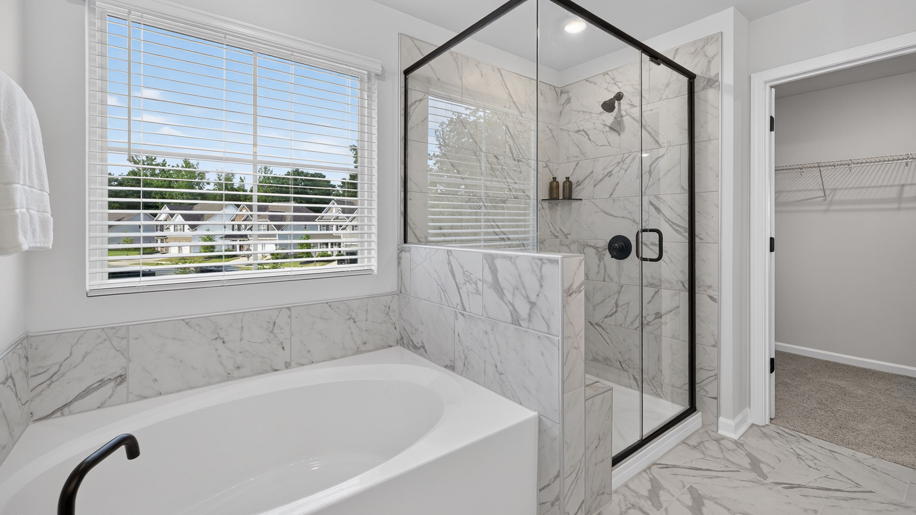 Primary bathroom with white cabinets, large bathtub ad shower