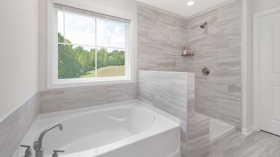 Primary bathroom with white cabinets, large bathtub ad shower