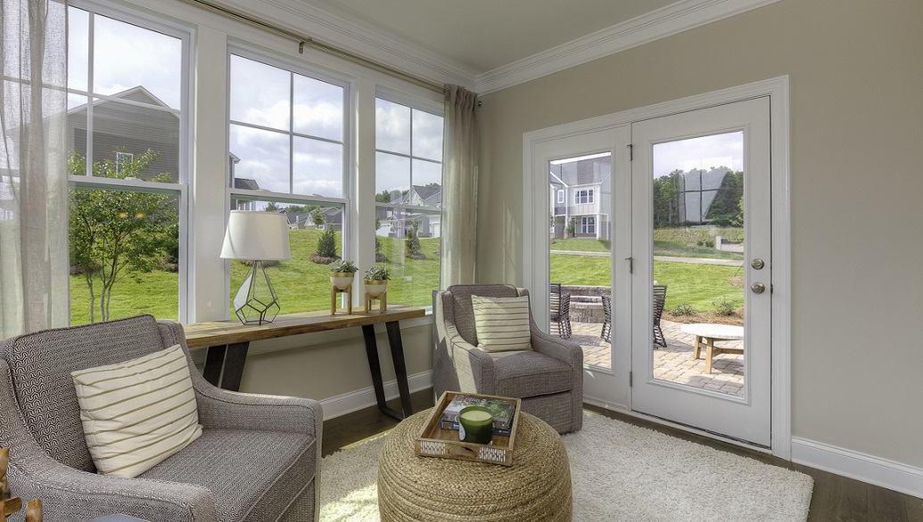 Sunroom with wood floors, surrounded by windows with a door to outside