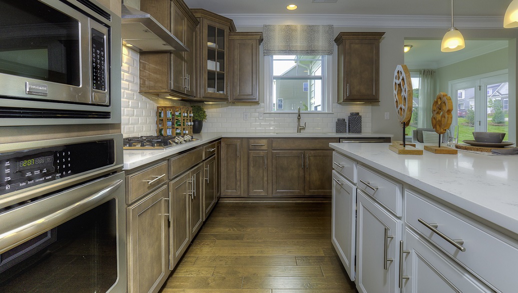 Kitchen and island with white cabinets, white rest of kitchen has brown cabinets