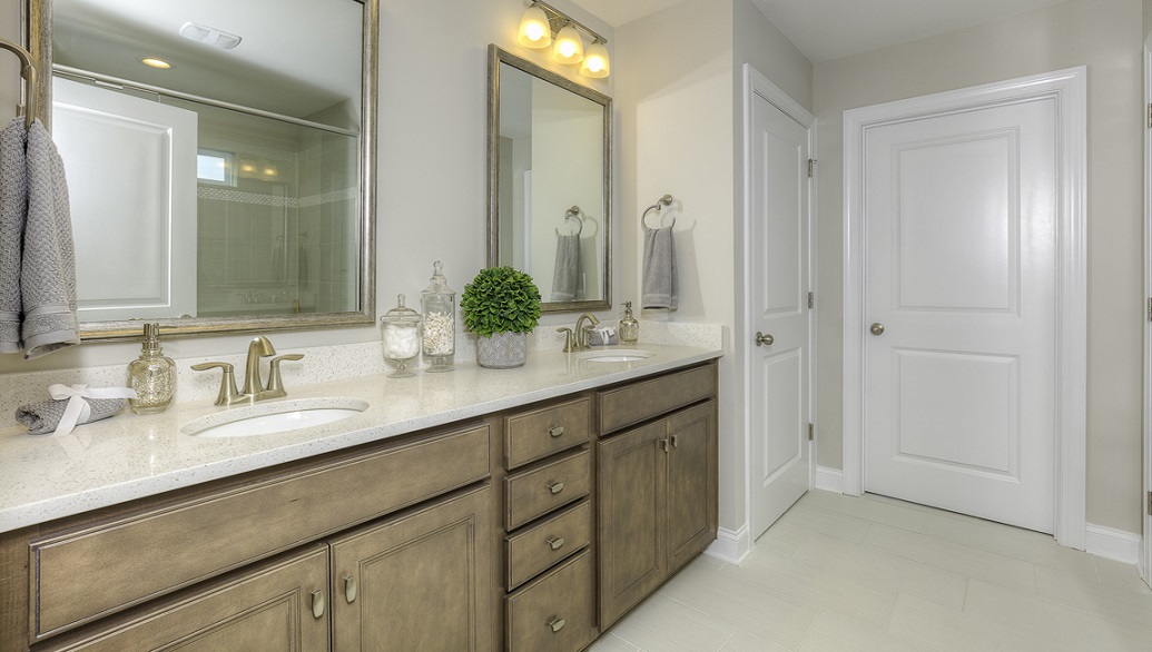 Primary bathroom with double sinks, white counters and brown cabinets