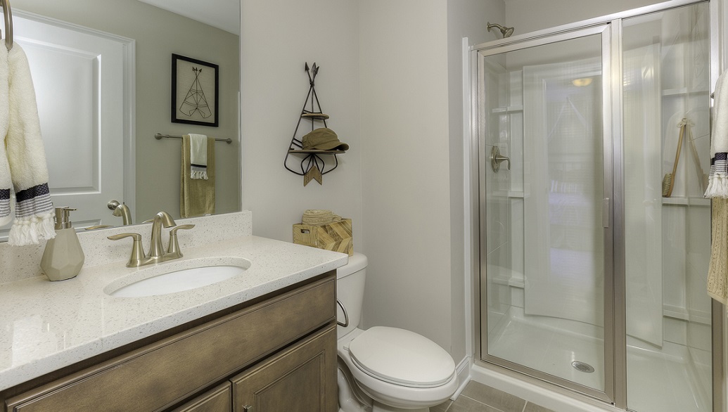 Bathroom with white counters, brown cabinets, and glass door shower