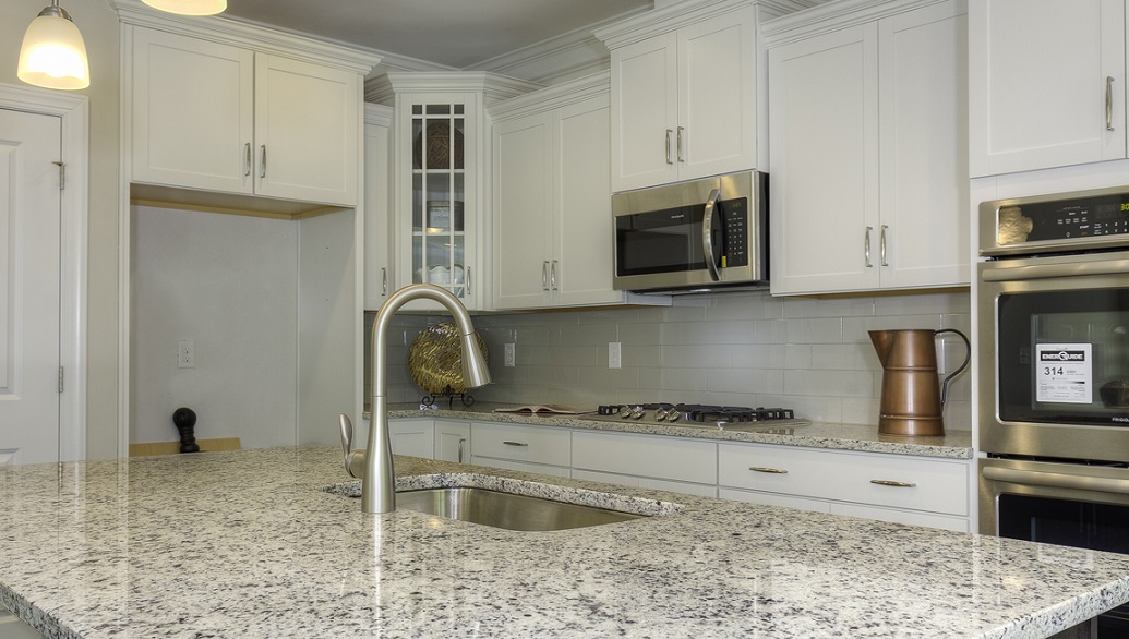 Kitchen and island with wood floors, white cabinets, and stainless steel appliances