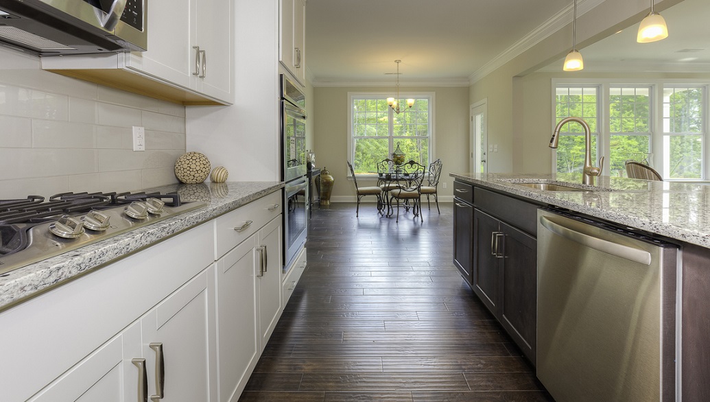 Kitchen and island with wood floors, white cabinets, and stainless steel appliances