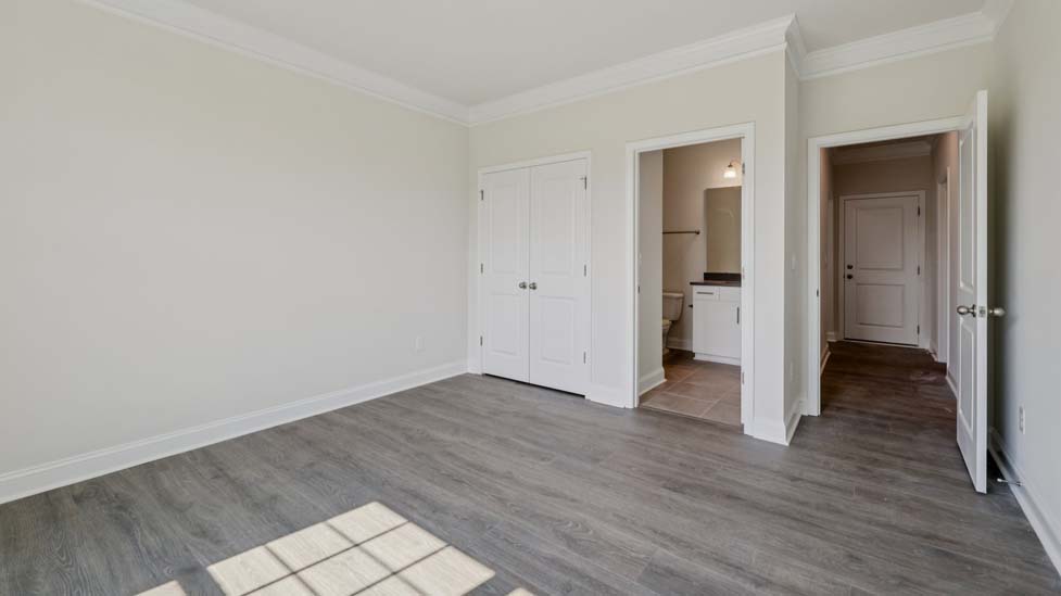 Carpeted guest room with large window and view of closet and entryway doors