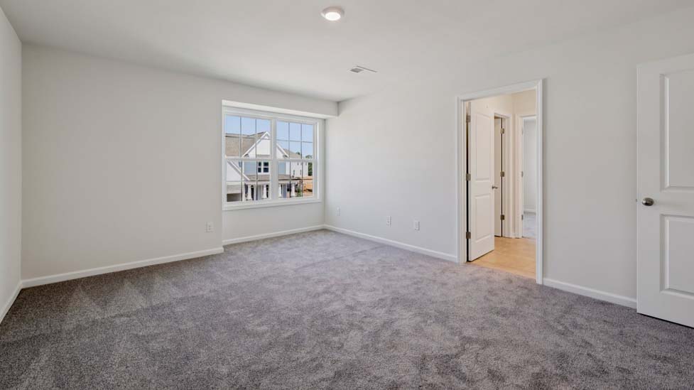 Carpeted guest room with large window and view of closet and entryway doors