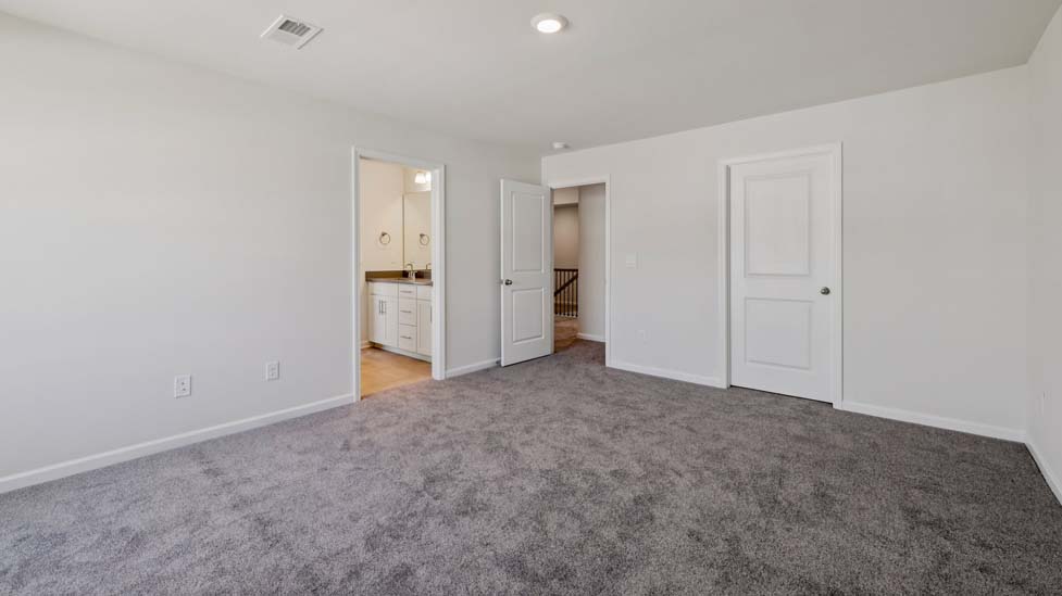 Carpeted guest room with large window and view of closet and entryway doors
