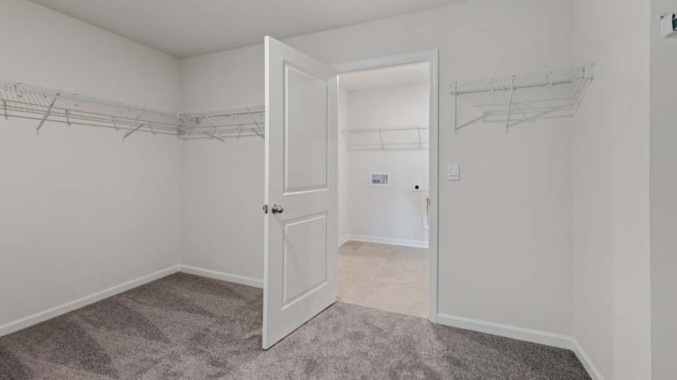 Primary bedroom walk in closet with hanging racks