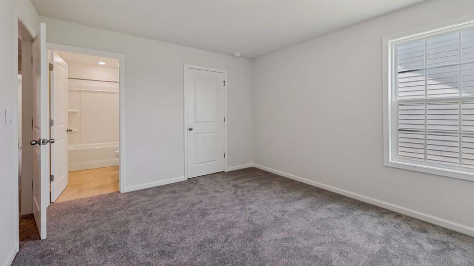 Carpeted bedroom with view of entryway doors and closet