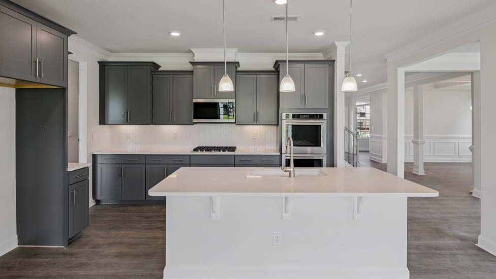 Kitchen and island with white cabinets, subway tile backsplash and stainless steel appliances