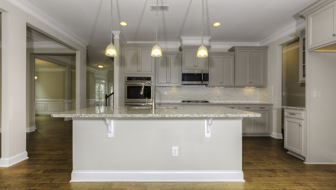 Kitchen and island with white cabinets, subway tile backsplash and stainless steel appliances