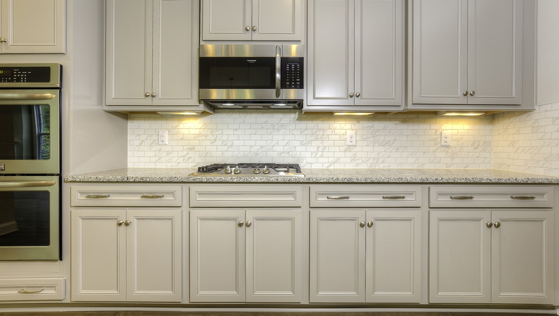 Kitchen and island with white cabinets, subway tile backsplash and stainless steel appliances