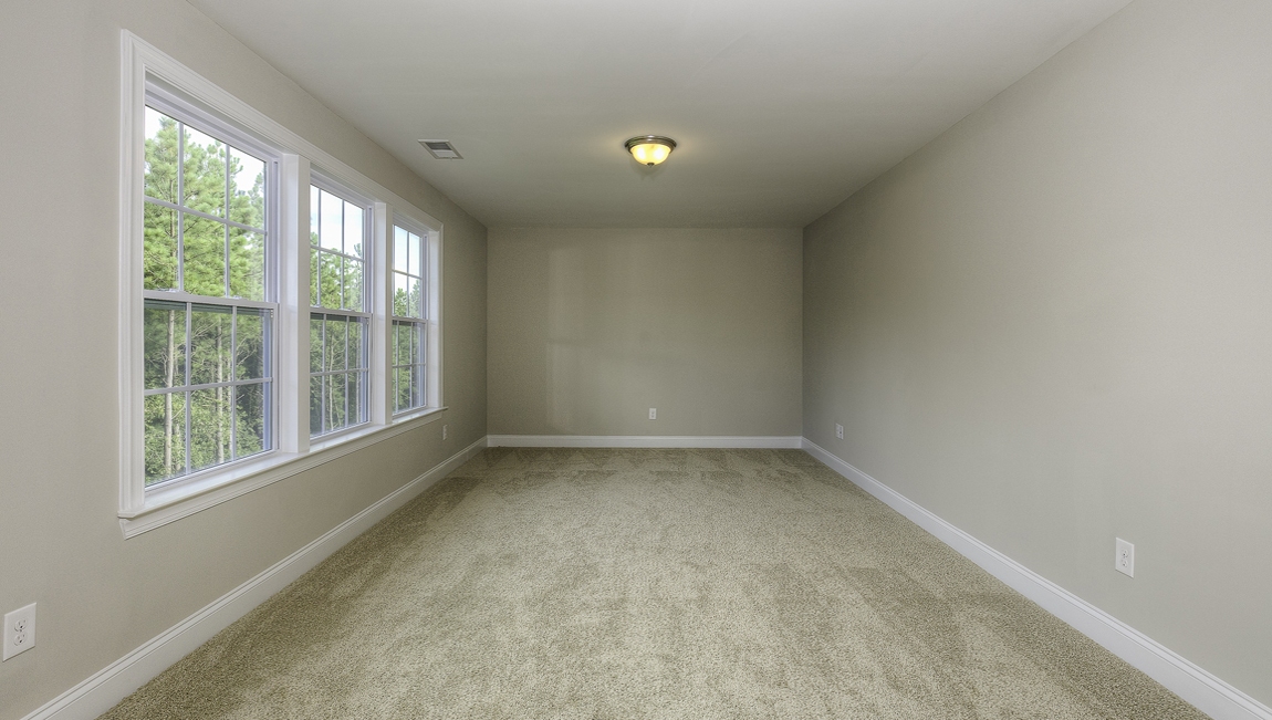 Primary bedroom with carpet and many large windows