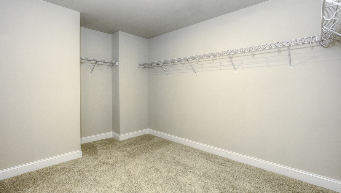 Primary bedroom walk in closet with hanging racks