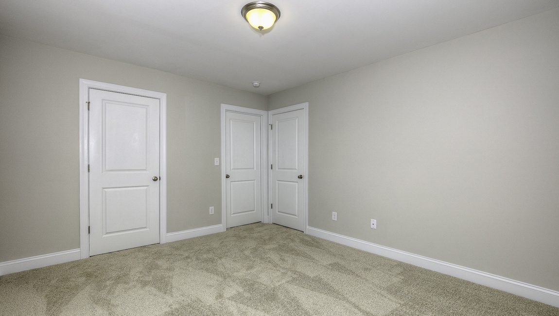 Carpeted bedroom with view of entryway doors and closet