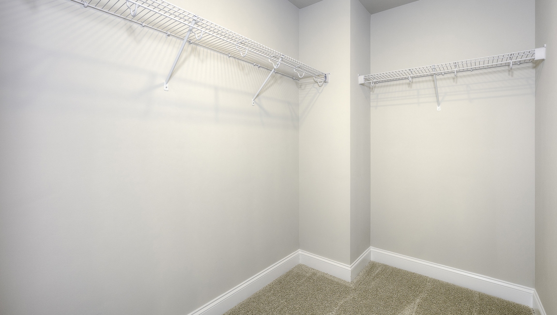 Carpeted walk in closet with hanging racks