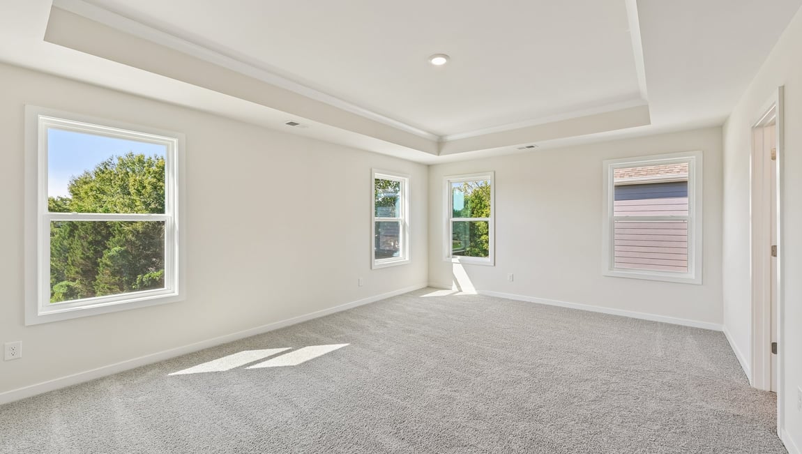 Primary carpeted bedroom with windows