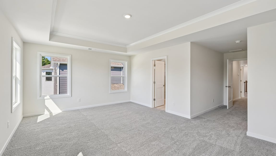 Primary carpeted bedroom with windows