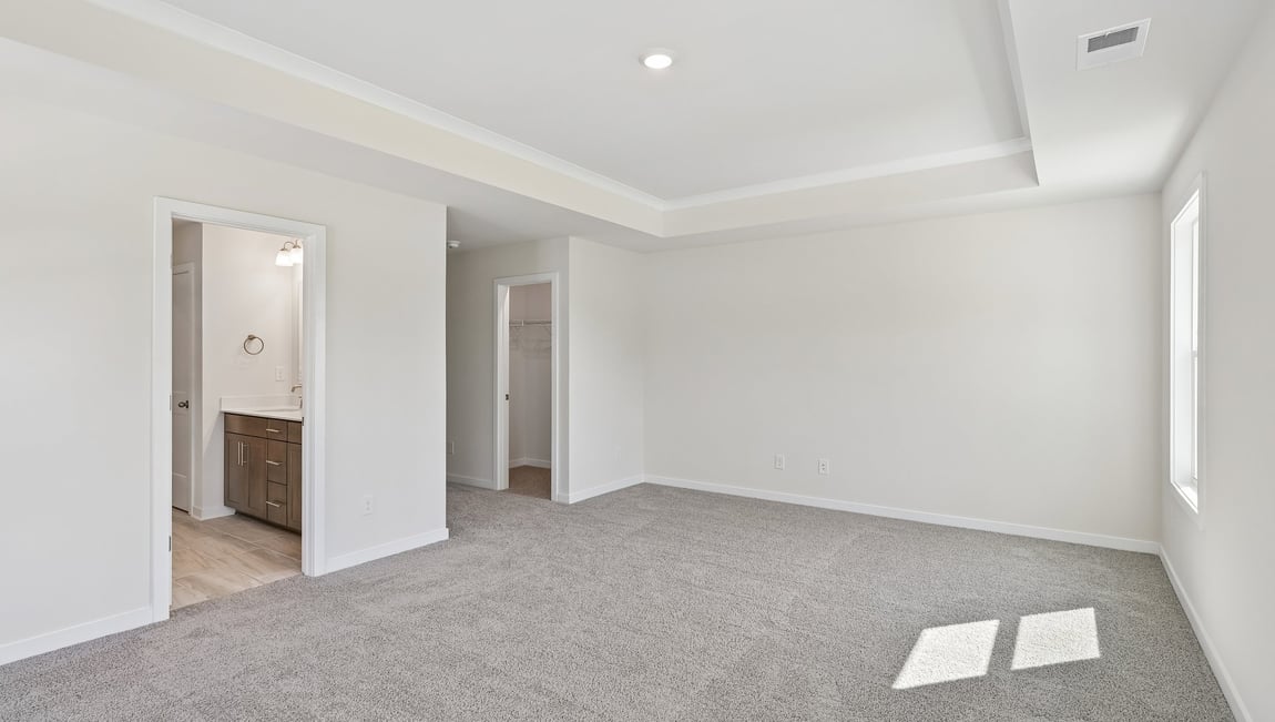 Primary carpeted bedroom with windows