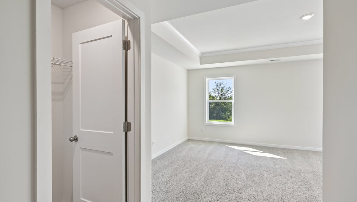 Primary carpeted bedroom with windows