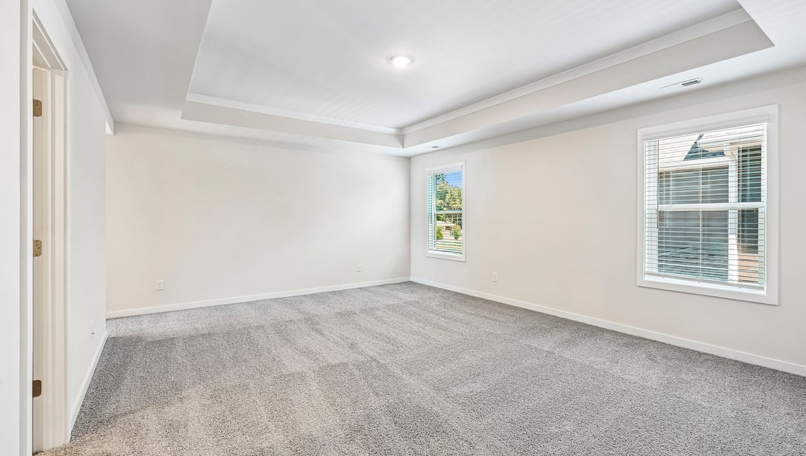 Primary carpeted bedroom with large windows