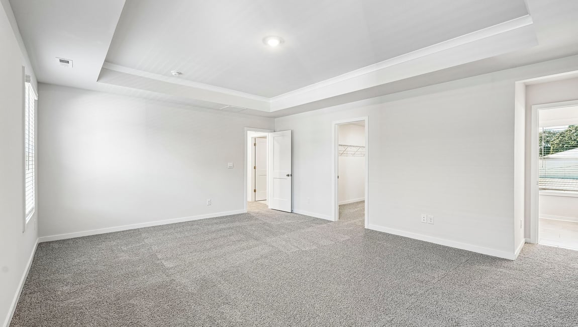 Primary carpeted bedroom with large windows
