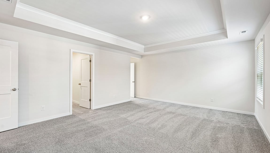 Primary carpeted bedroom with large windows