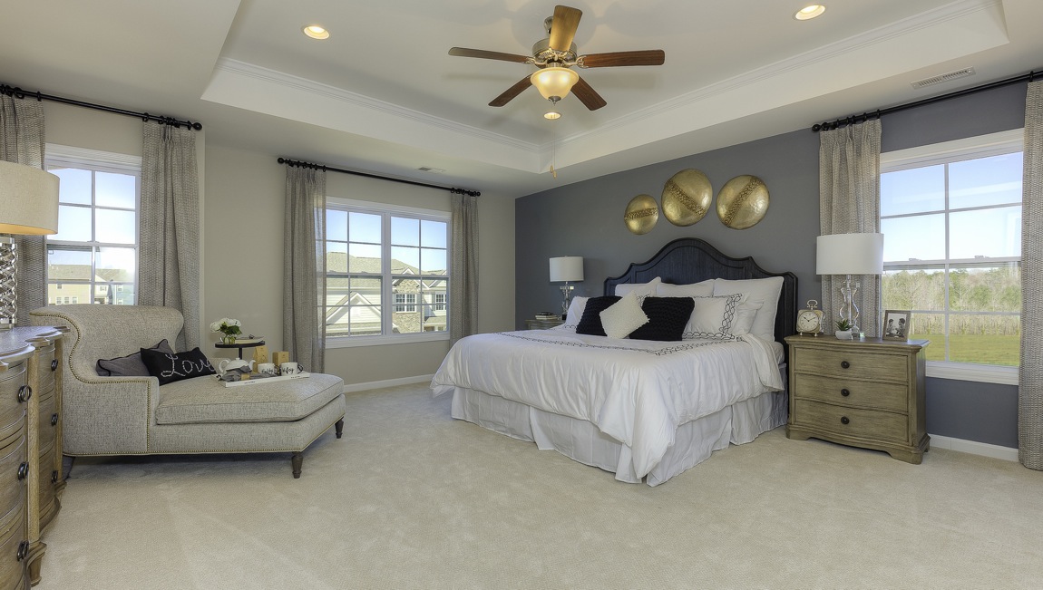 primary bedroom with ceiling fan and large windows