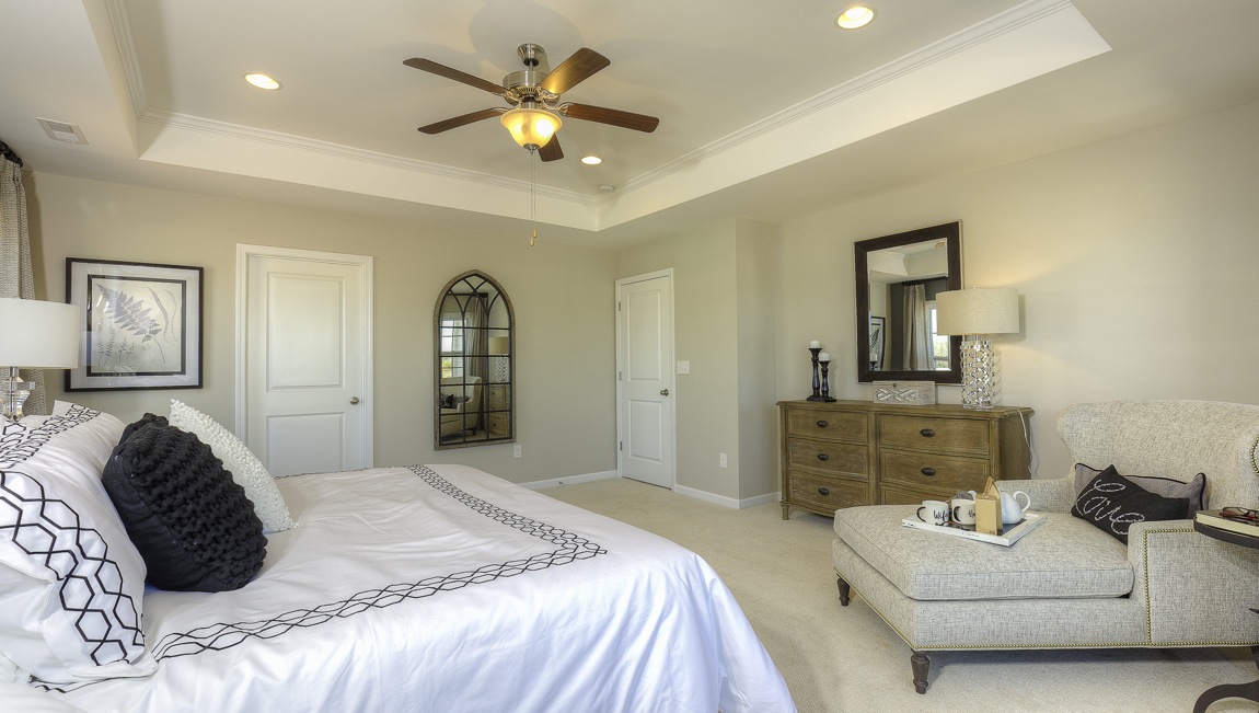 primary bedroom with ceiling fan and large windows