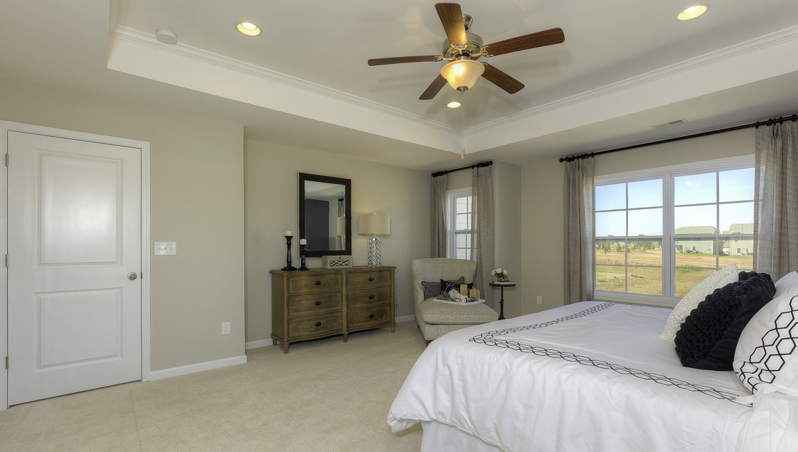 primary bedroom with ceiling fan and large windows