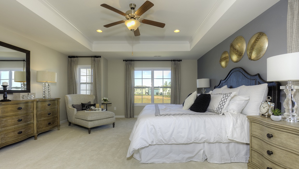 primary bedroom with ceiling fan and large windows