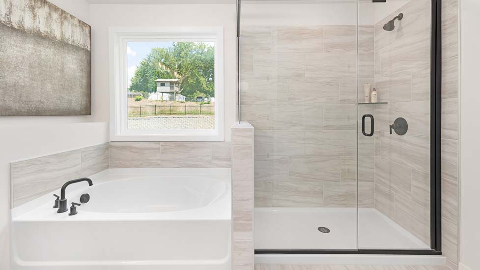 bathroom with large bathtub and standing shower with double sink vanity