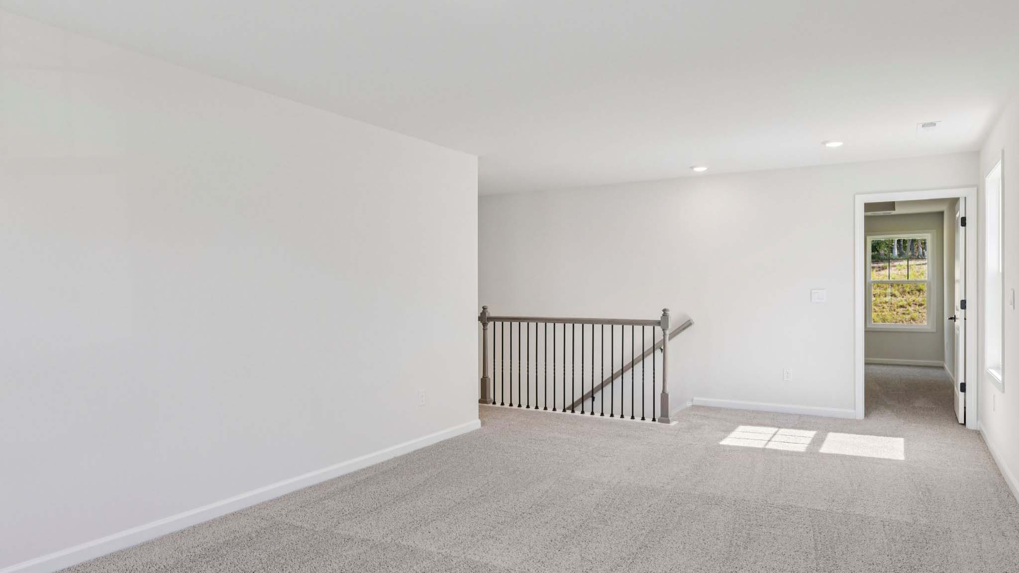 Carpeted upstairs loft with large windows