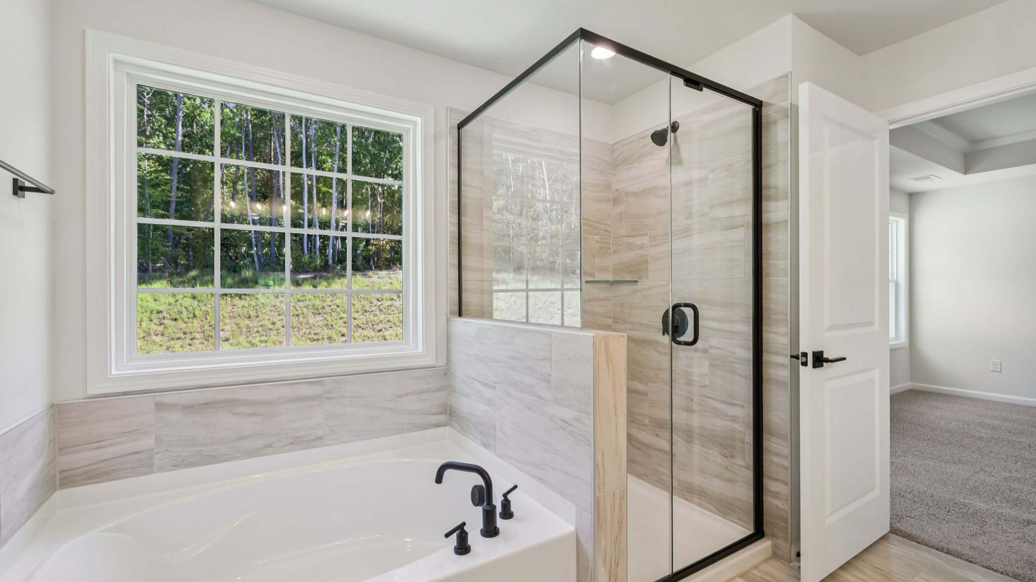 Primary bathroom with large window, bath, and standing shower