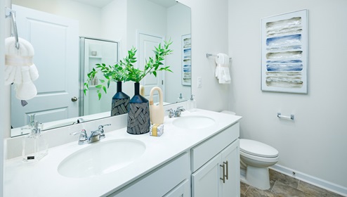 Adair Woods Winston model bathroom with double sinks, white cabinets and counters.
