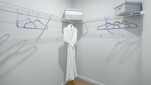 Adair Woods Winston model carpeted walk in closet with built in hanging racks